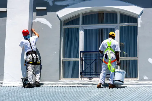 Two painters in harnesses repainting a historic commercial facade in Glenwood South