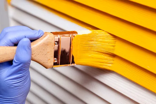 Brushing an accent color onto louvered shutters on a Mordecai house